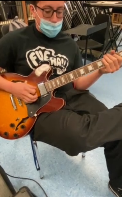 Adrian playing an electric guitar in a music room.